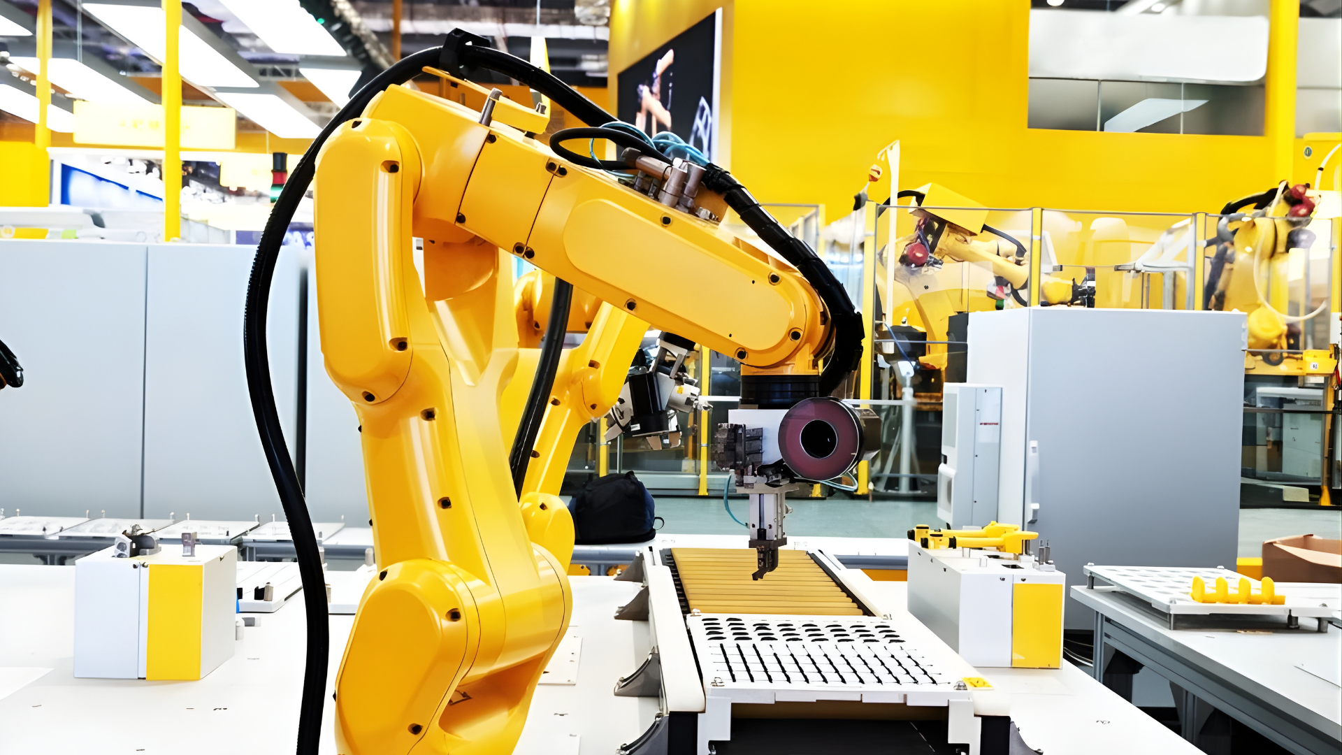 Yellow industrial robotic arm operating on an automated manufacturing workstation, positioning a tool over a precision component inside a modern factory environment.